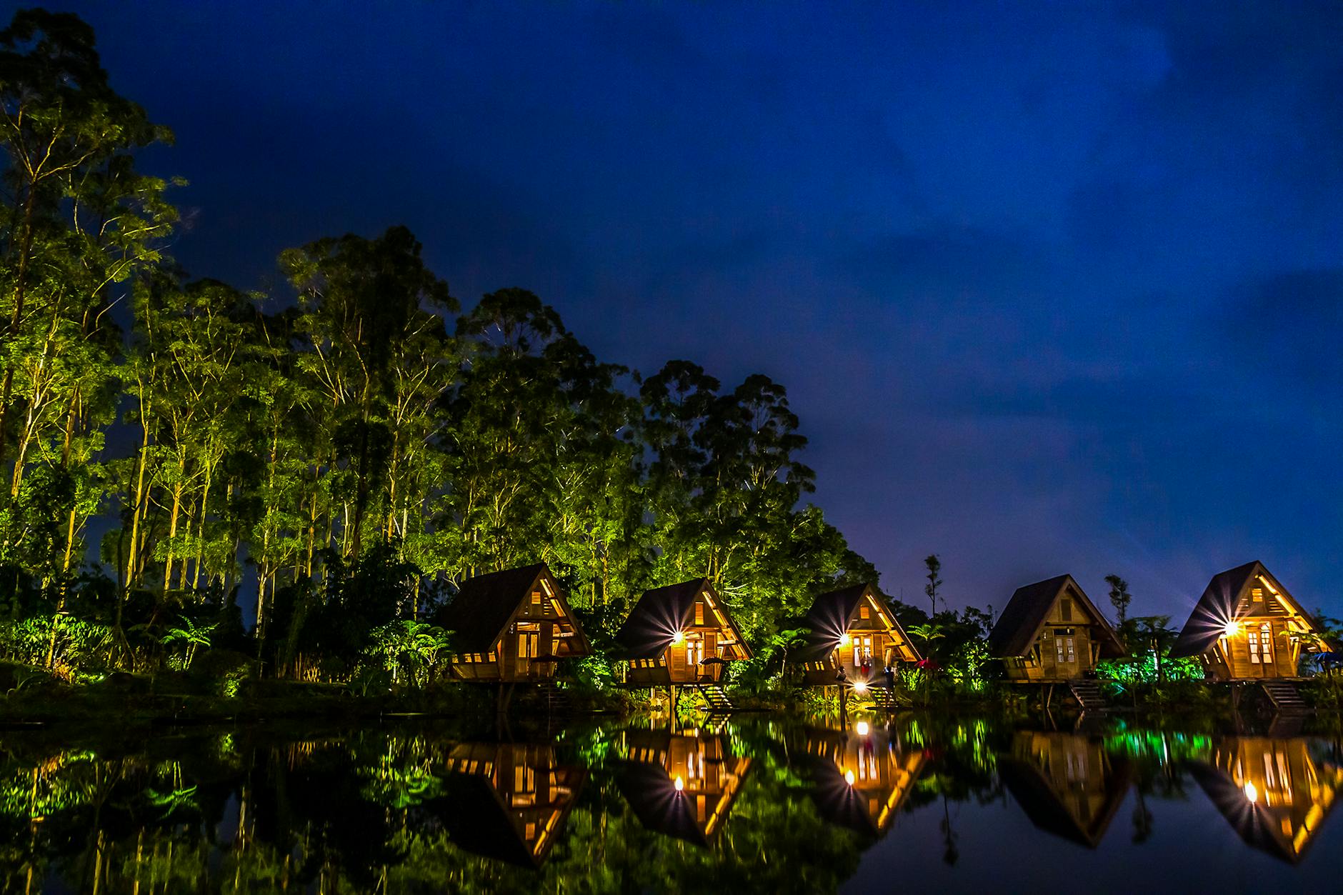 brown wooden house near body of water during night time