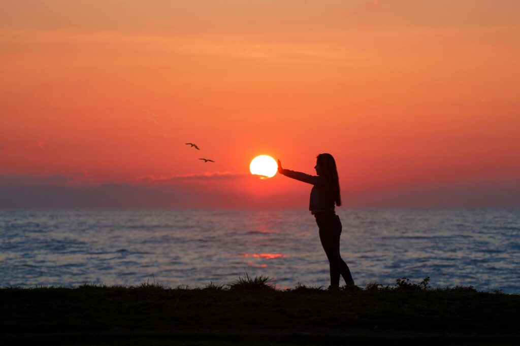 photo of woman standing on seashore during dawn